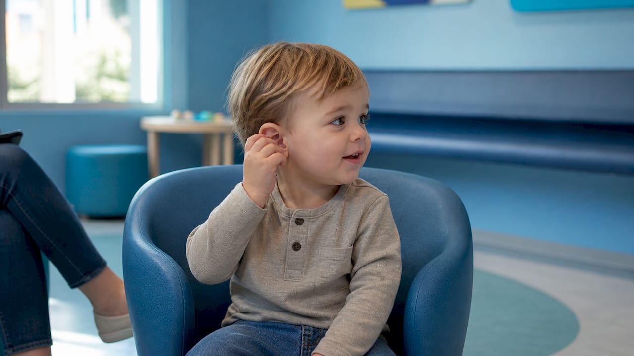 Child touching outer ear in clinic