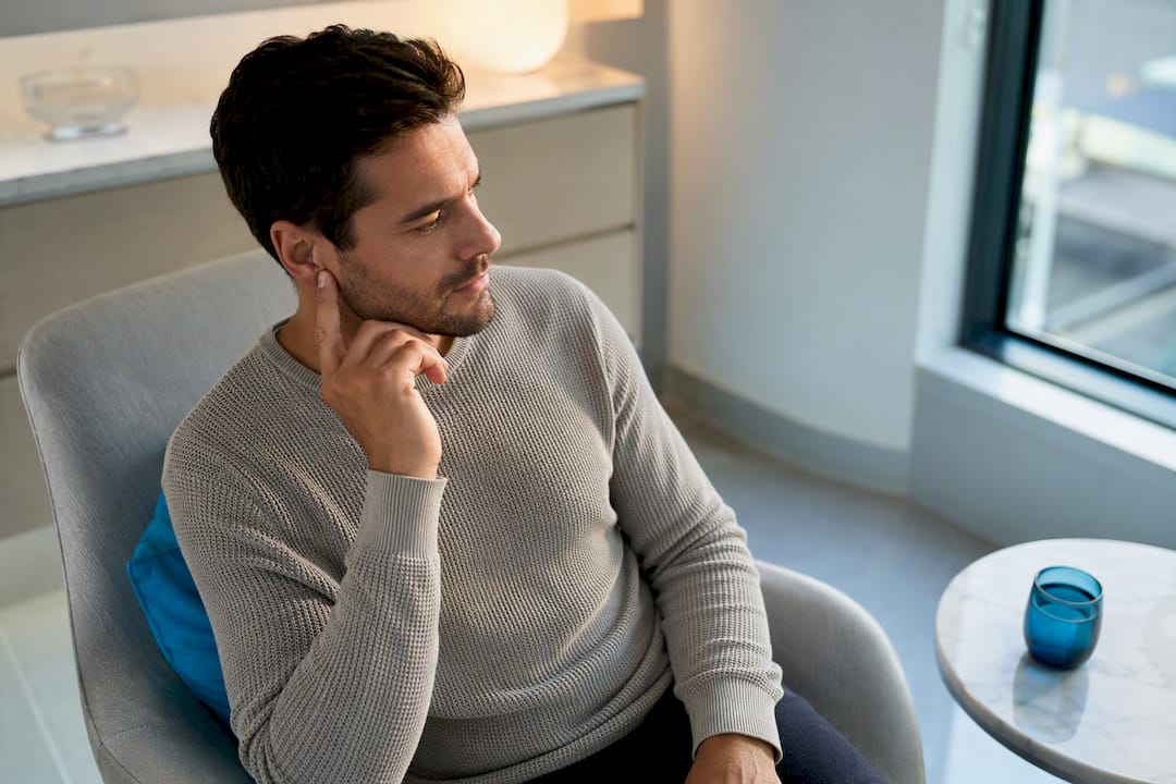 Adult gently touching outer ear in clinic
