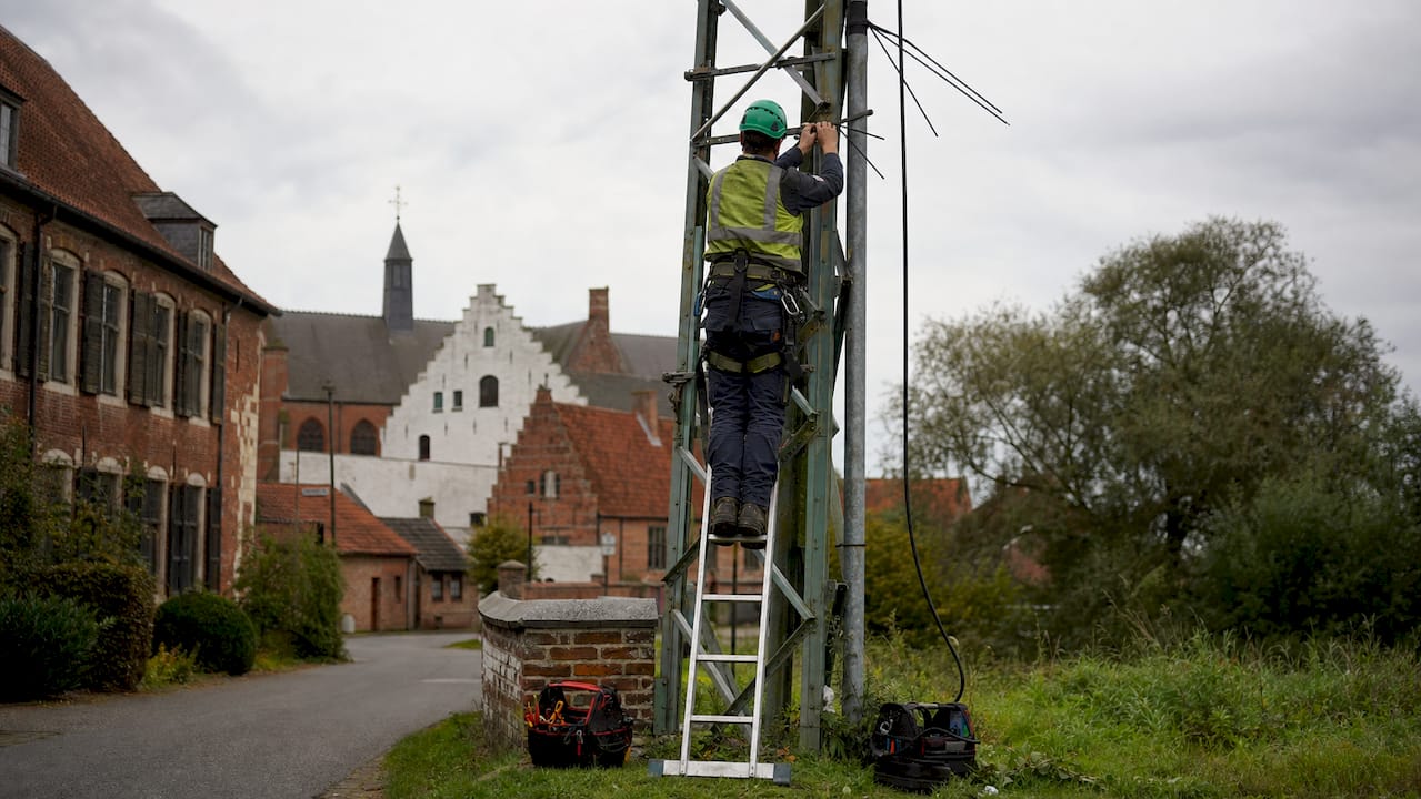 Een monteur is buiten aan het werk om stroomkabels te onderhouden.