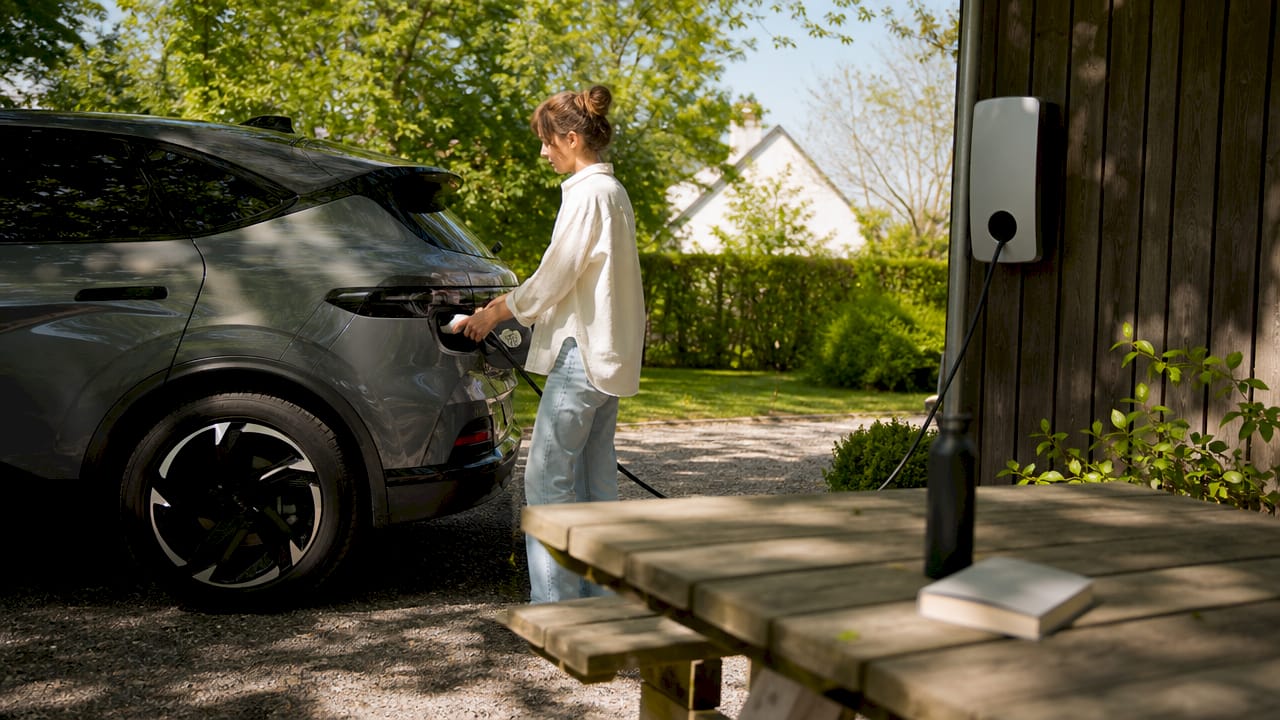 Vrouw sluit haar elektrische auto aan op de thuislader