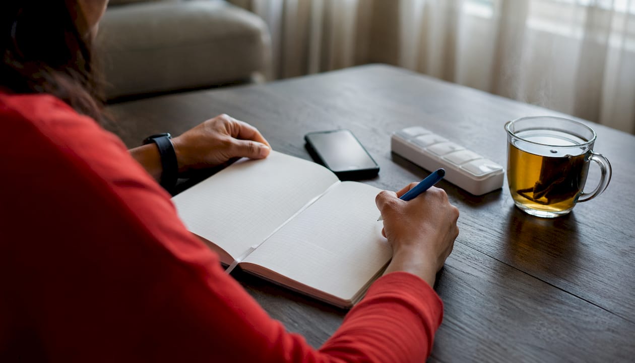 Patient writing symptom diary at home