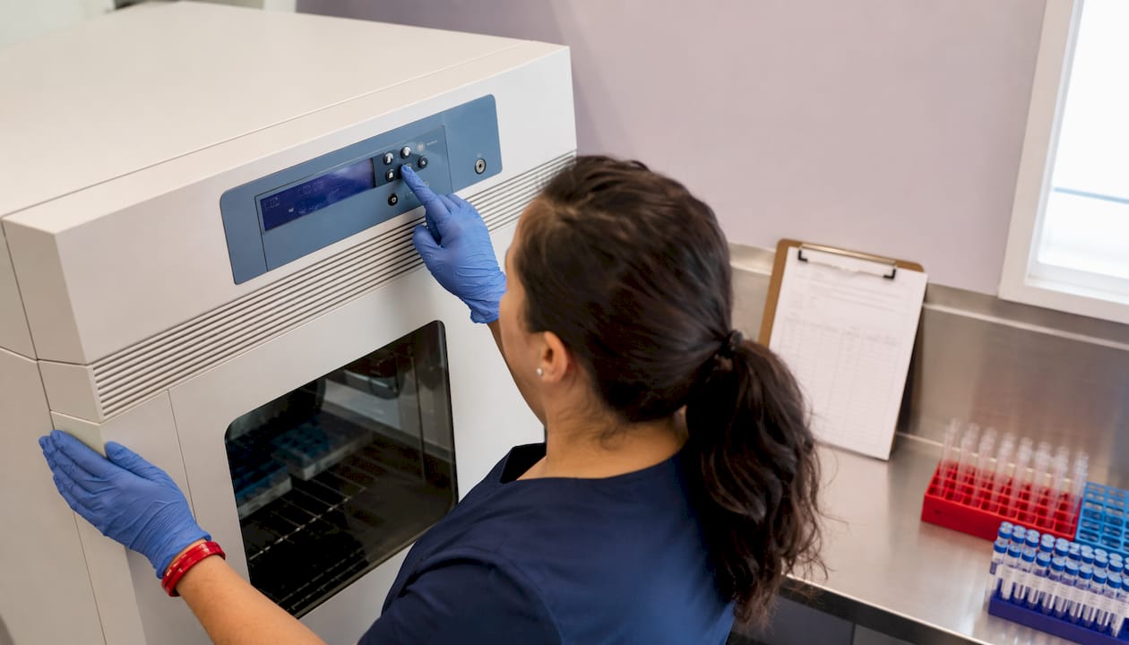 Hands adjusting specimen incubator temperature