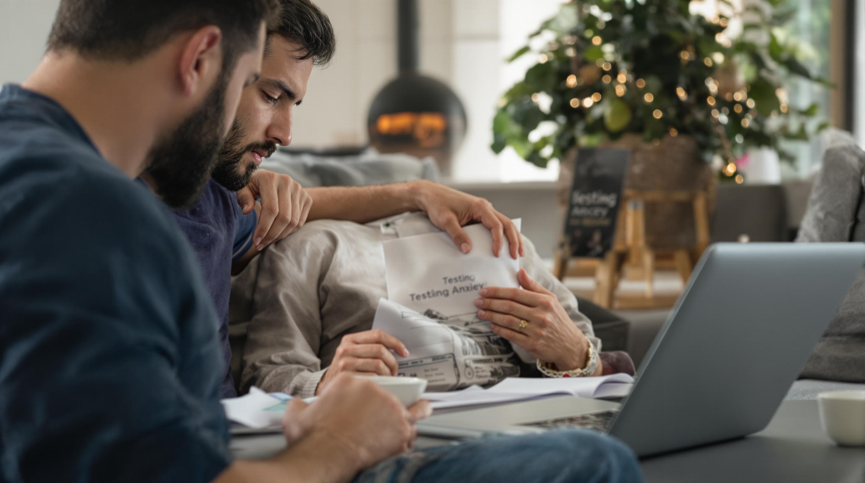 Man and partner reviewing health paperwork with 'Testing Anxiety' on laptop
