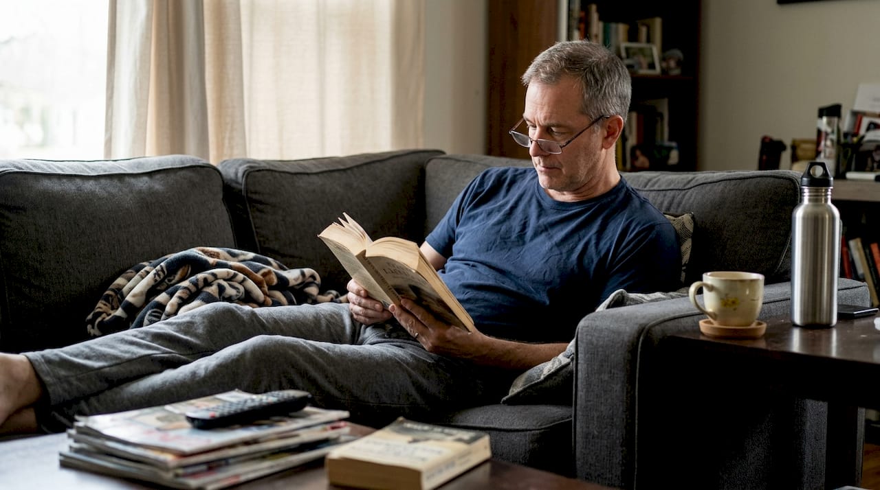 Man resting on sofa with water and tea for voice recovery