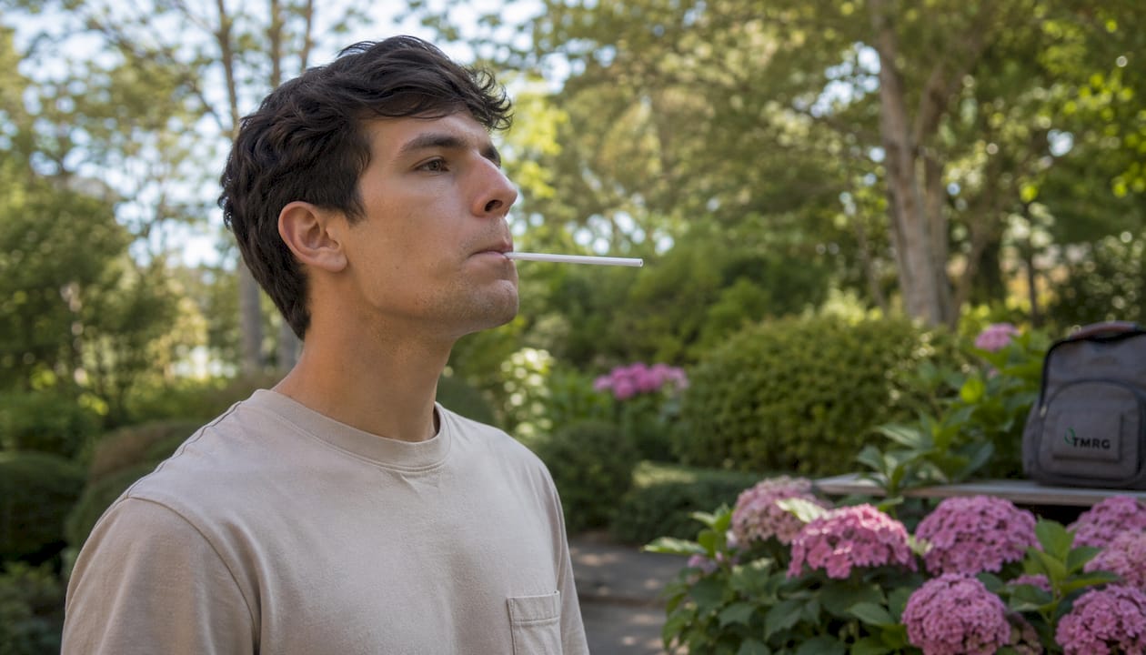 Young man doing straw phonation exercise