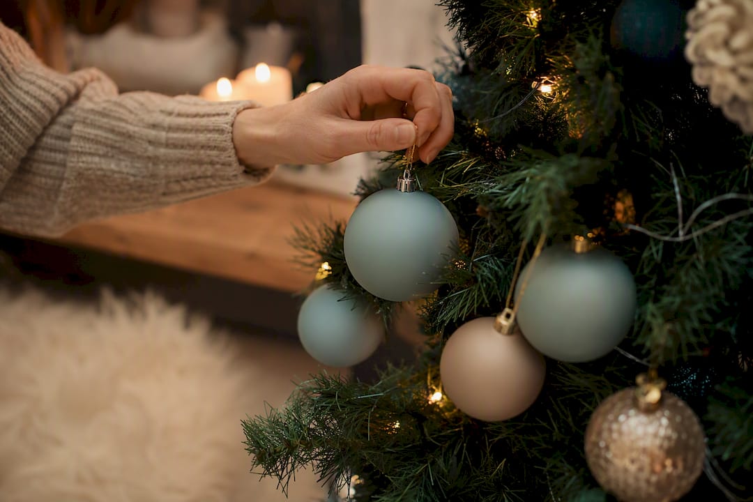 Hand placing dog-safe shatterproof ornaments on Christmas tree