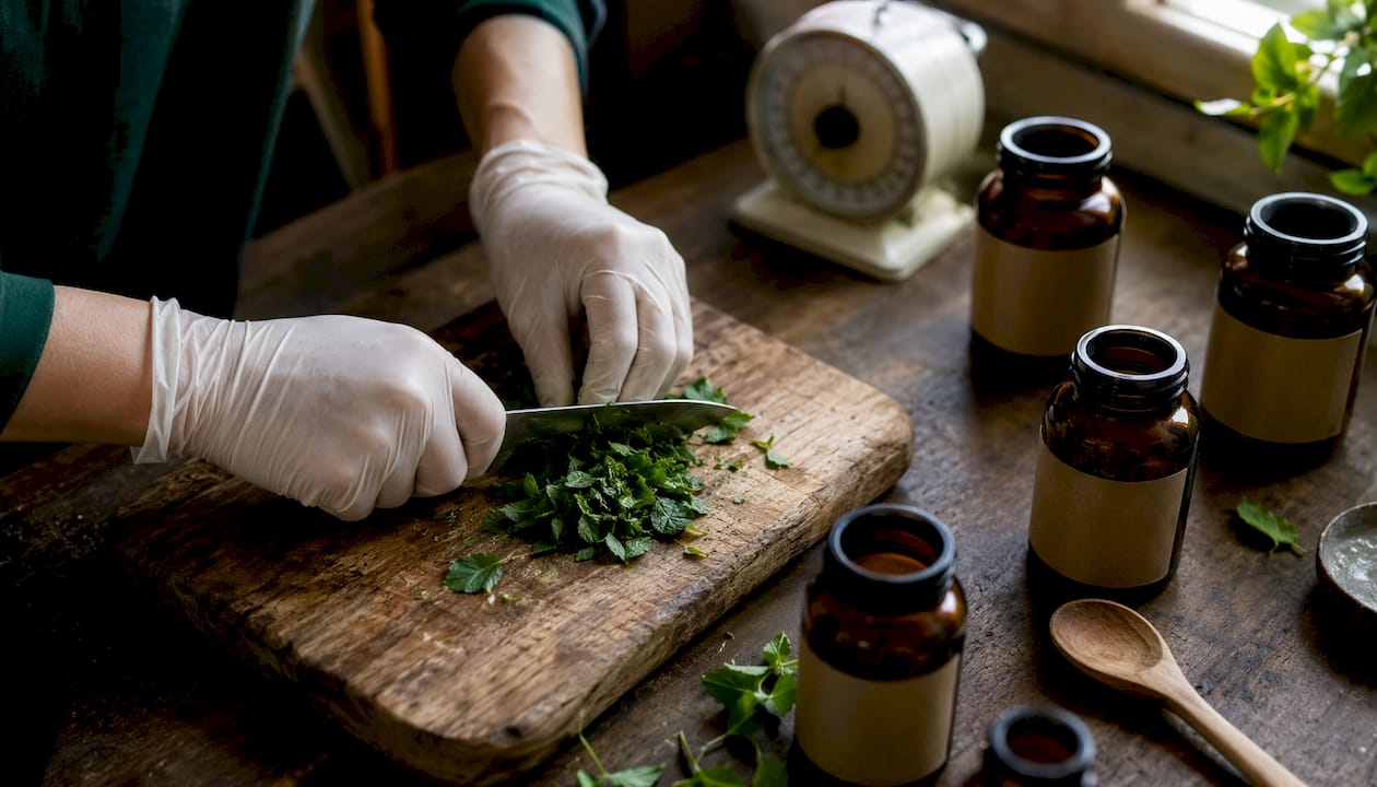 Hands grinding peppermint leaves with mortar and pestle