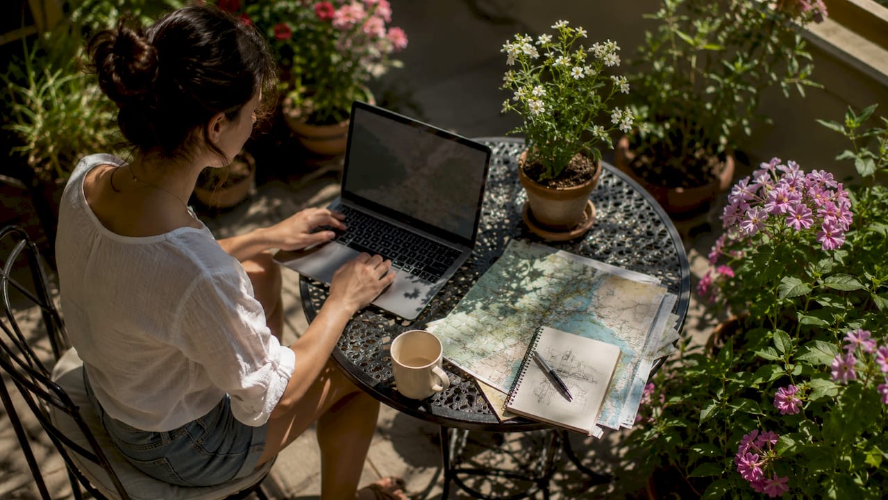 Hands selecting map location on laptop