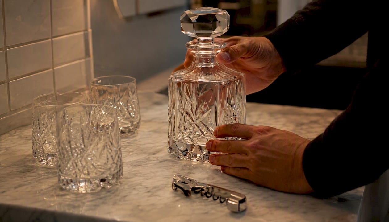 Hands placing engraved crystal decanter as gift