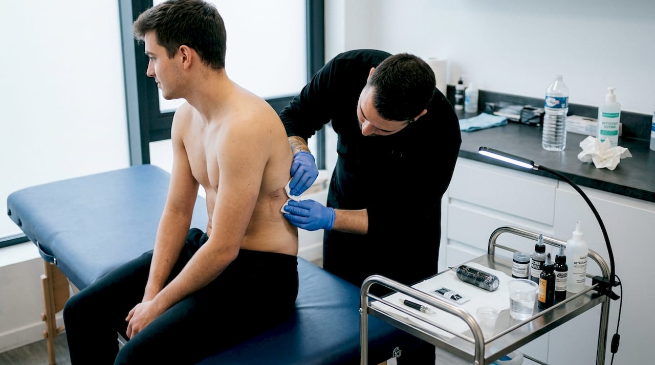 Le tatoueur s'apprête à préparer la zone des côtes de son client avant de commencer le tatouage.