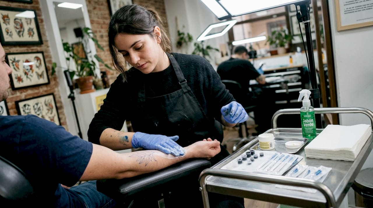 El tatuador aplica crema en la piel antes de comenzar con el tatuaje.
