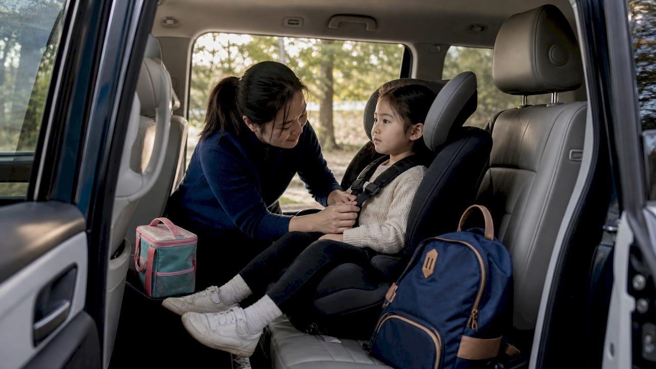 Child buckled in car seat with parent securing straps