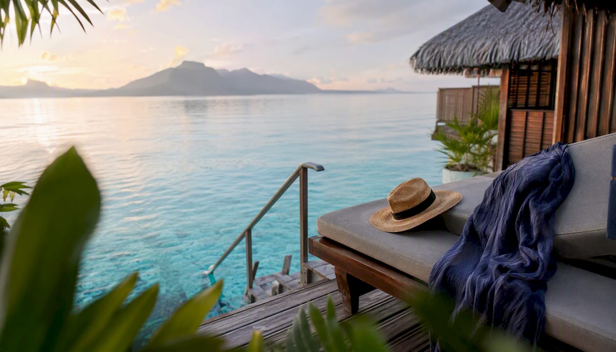 Overwater bungalow veranda overlooking turquoise lagoon at golden hour