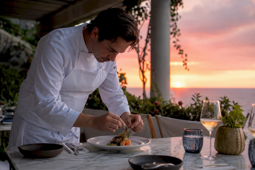 Chef plating dinner on terrace at sunset