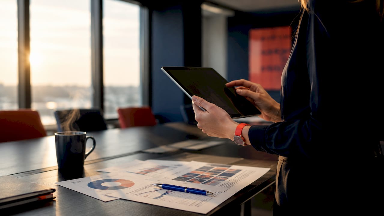 Eine Frau hält ein Tablet in der Hand und analysiert darauf Sicherheitsdaten.
