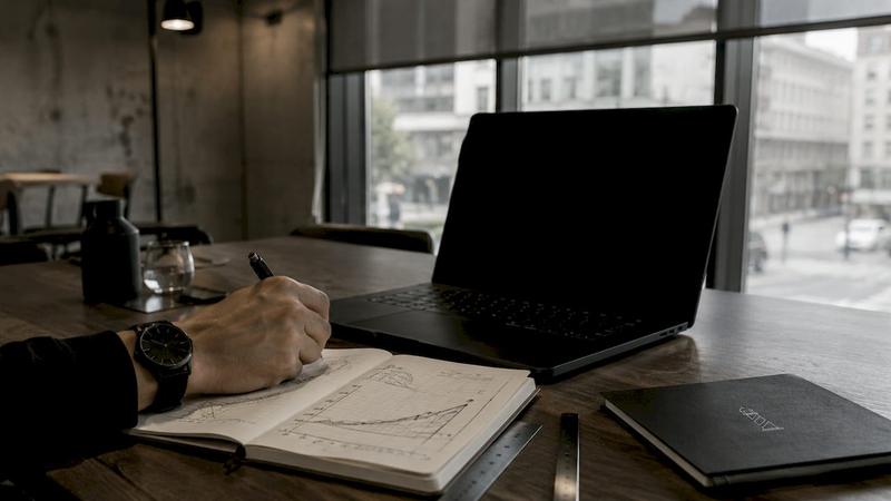 Des mains qui prennent des notes et ajoutent des commentaires sur des graphiques dans un carnet.