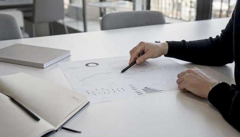 Des mains examinent attentivement un tableau de bord imprimé regroupant les données SEO.