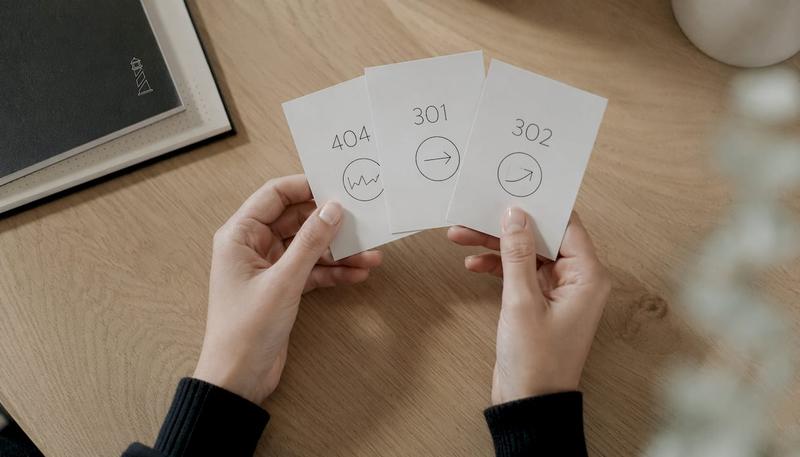 Des mains tenant des cartes illustrant les principaux codes HTTP utilisés en SEO