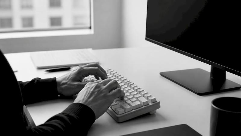 Des mains s’activent sur un clavier dans un espace de travail épuré, dédié au développement et au référencement.