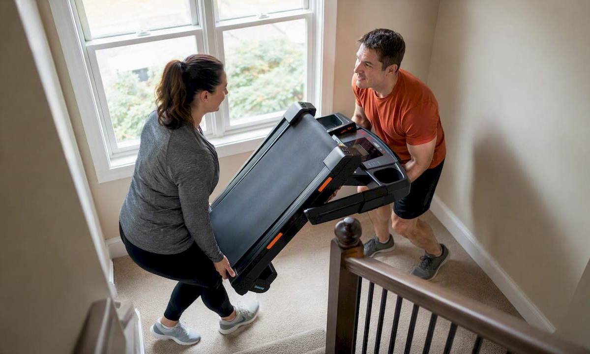 Team lifting treadmill up stairs carefully