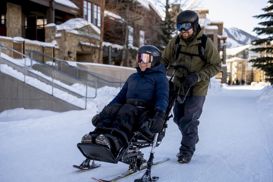 Adaptive skier and instructor at a base village