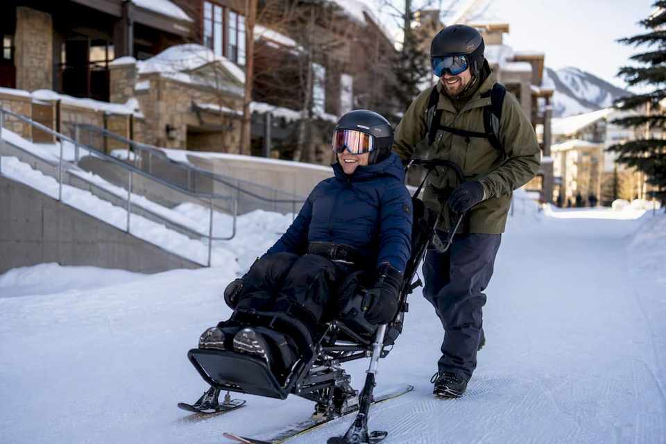 Adaptive skier and instructor at a base village