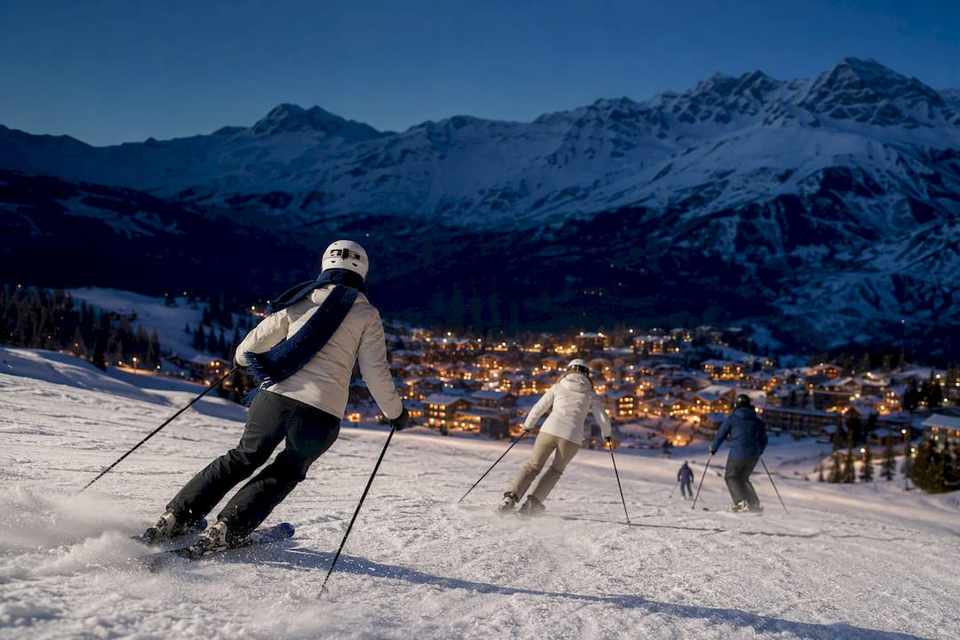Skiers descending toward a Christmas village
