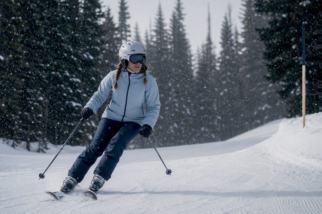 Beginner skier on snowy tree-lined run