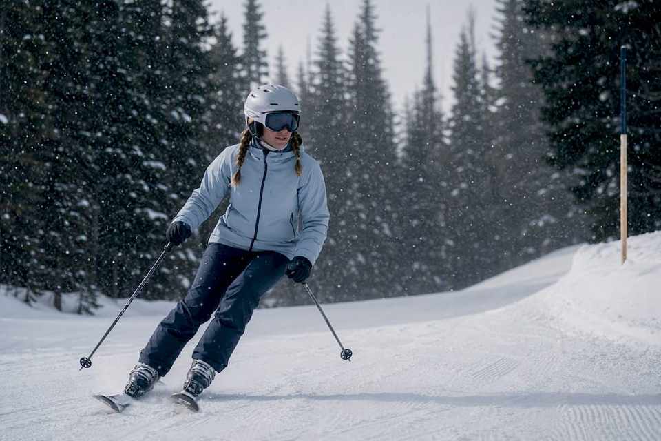 Beginner skier on snowy tree-lined run